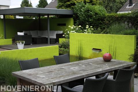 Kleurrijke tuin met vijver en terrasoverkapping met loungeset