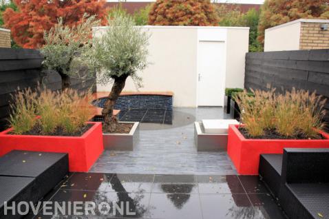 Moderne tuin met strakke lijnen, rode bloembakken en zithoek