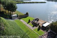 Tuin aan het water met gazon en vlonder