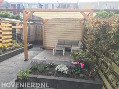 Tuinaanleg met sierbestrating, plantenbak en pergola met harmonicadoek