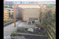 Tuinaanleg met sierbestrating, plantenbak en pergola met harmonicadoek