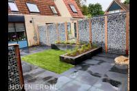 Tuinaanleg met bestrating, gras, plantenbakken en schanskorf schutting