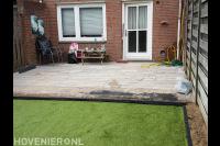 Achtertuin met natuursteen bestrating en kunstgras
