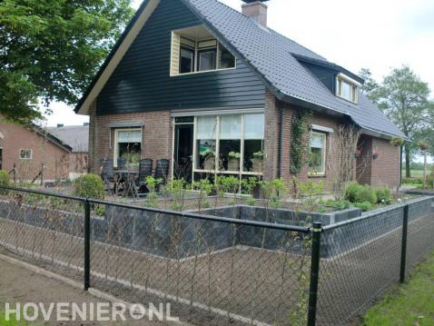 Gaashekwerk om voortuin met plantenbakken van stapelblokken en terras