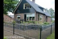 Gaashekwerk om voortuin met plantenbakken van stapelblokken en terras