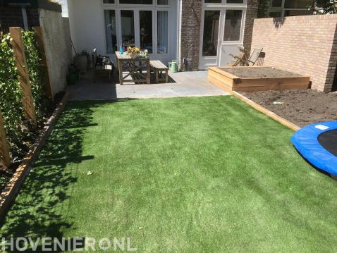 Achtertuin met terras, kunstgras en houten plantenbak