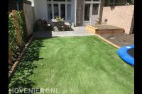 Achtertuin met terras, kunstgras en houten plantenbak