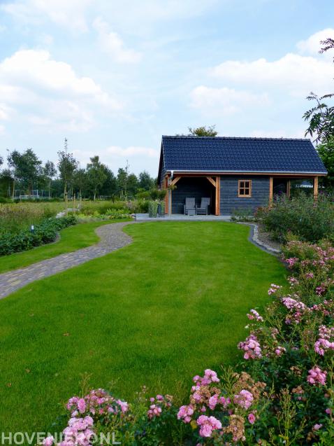 Tuin met gazon en grote houten schuur met veranda