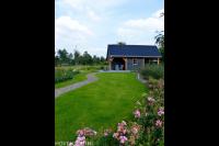 Tuin met gazon en grote houten schuur met veranda