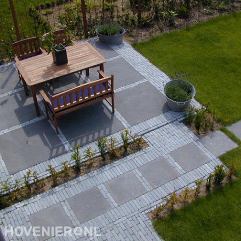 Terras van klinkers en grote tuintegels met houten tuinset