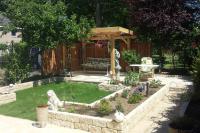 Compacte tuin met gazon, plantenbakken en houten overkapping