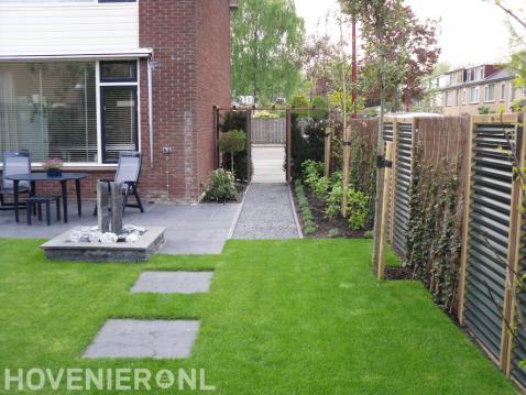 Achtertuin met terras, waterornament en gazon met stapstenen