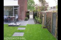 Achtertuin met terras, waterornament en gazon met stapstenen