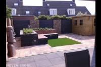 Relaxtuin met zitbank, kunstgras, schuurtje en steenschuttingen 1