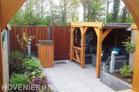 Tuinaanleg met bestrating, plantenbakken en houten veranda