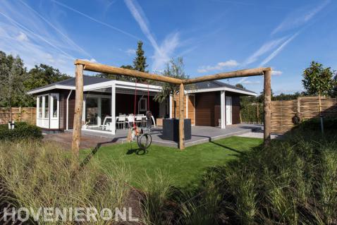 Robuuste houten pergola met schommel bij gazon van kunstgras