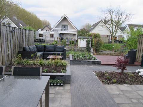 Tuin met hardhouten vlonder, borders van stapelblokken en loungeset