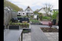 Tuin met hardhouten vlonder, borders van stapelblokken en loungeset
