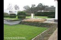 Grote open tuin met strakke lijnen met vijver en gazon
