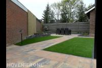 Tuin met terrasoverkapping, kunstgras en bestrating van natuursteen 2