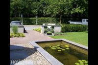 Voortuin met strakke vijver en grindpad met stapstenen