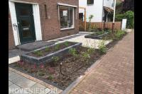 Voortuin met plantenbakken, grind en jonge haagplanten