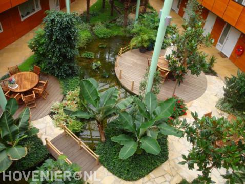 Tropische binnentuin met vijver, bruggetje en vlonders