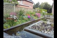 Kleurrijke beplanting langs strakke vijver