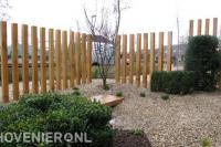 Onderhoudsarme tuin met grind en decoratie van hoge houten palen