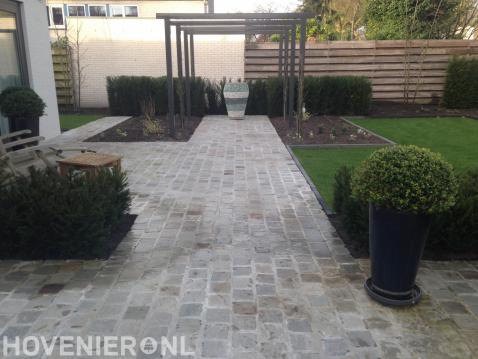 Tuin met pergola en bestrating van koppelstones.