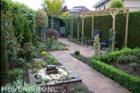 Kleine achtertuin met houten pergola en waterornament 1