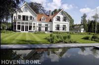 Villatuin met groot gazon, vijver en veel groen