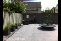 Moderne achtertuin met grote tegels en siergras in bloempotten