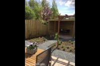 Tuin met houten overkapping, pergola, grindpad en nieuwe beplanting