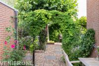 Romantische stadstuin met veel groen en oud gebakken bestrating