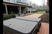 Tuin met grote houten overkapping en jacuzzi met vlonder