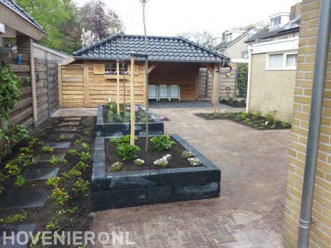 Tuin met plantenbakken en houten overkapping met berging