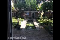 Tuin met vijver en strak gesnoeide hagen