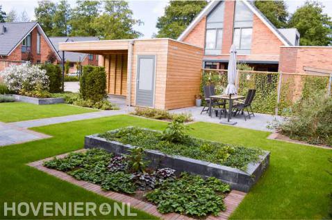 Moderne tuin met gazon, terras en houten schuurtje met overkapping