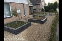 Voortuin met grind en plantenbakken van stapelblokken