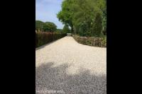 Lange oprit van grind omgeven door beukenhagen