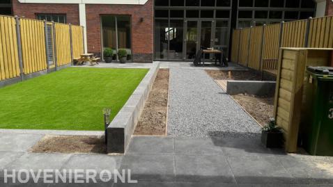 Moderne tuin met terras, bestrating, kunstgras en houten schutting