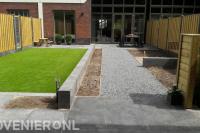 Moderne tuin met terras, bestrating, kunstgras en houten schutting