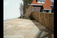 Terras van keramische tegels en tuinafscheiding van rieten matten