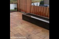 Tuinaanleg met tegels in wildverband, plantenbak en houten schutting