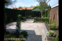 Achtertuin met prieel, taxushaag en bestrating van waaltjes