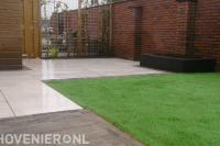 Achtertuin met bestrating en grasmat