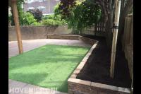 Achtertuin met siertegels, kunstgras en verhoogde border