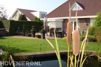 Strakke achtertuin met terras, gazon en vijver