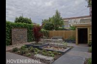 Tuin met schanskorven, vijver en houten schuurtje 1